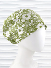 Euro Pixie style surgical scrub cap by JensCaps with white daisies and flowers all over a light green background cotton fabric and displayed on a mannequin head.