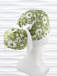 Ponytail style surgical scrub cap with white daisies and flowers all over a light green cotton fabric, finished with a grosgrain ribbon tie, and displayed on a mannequin head.