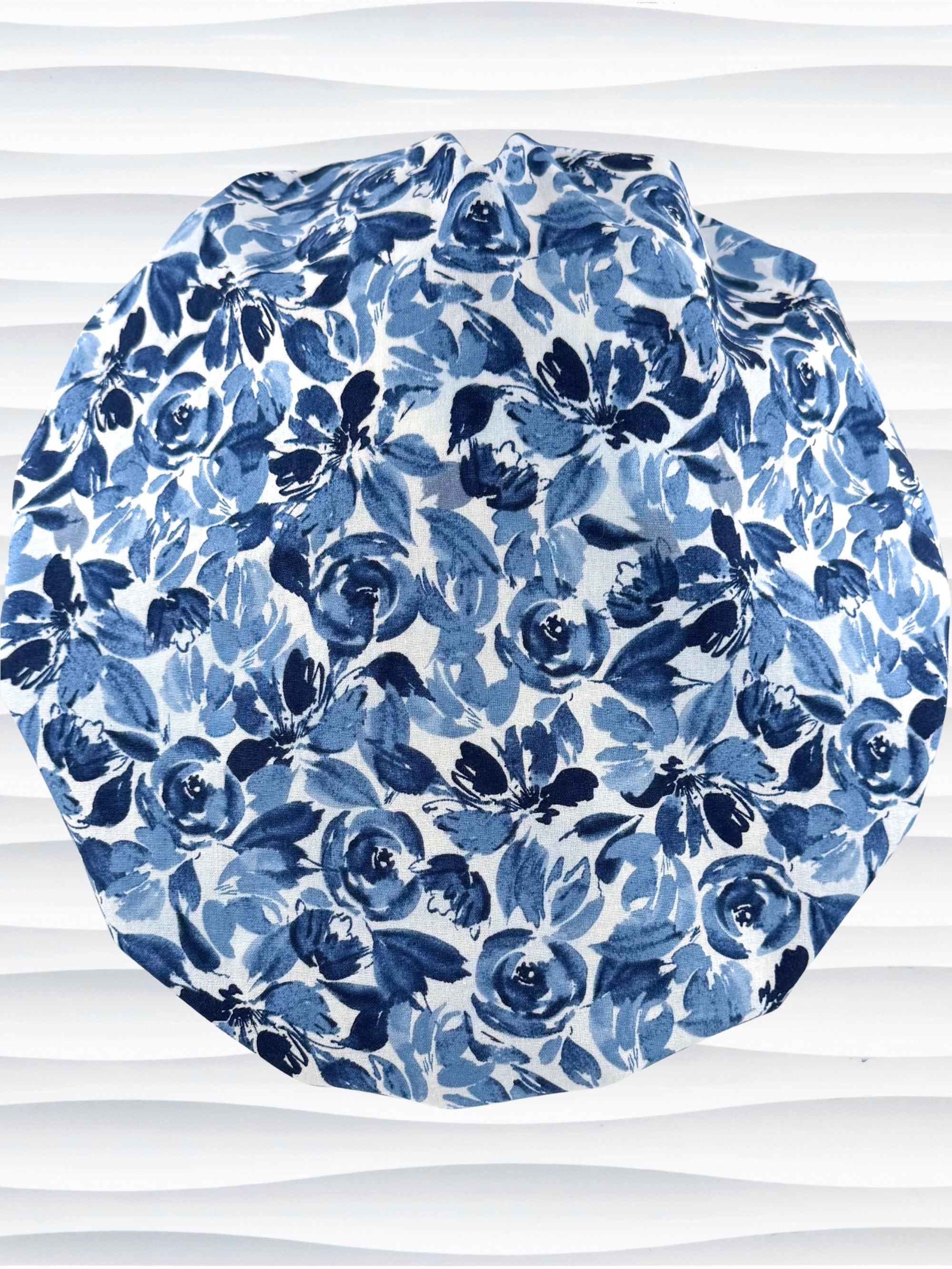 Bouffant style surgical scrub cap by JensCaps with flowers in varying shades of blue with a white background displayed on a white mannequin head.