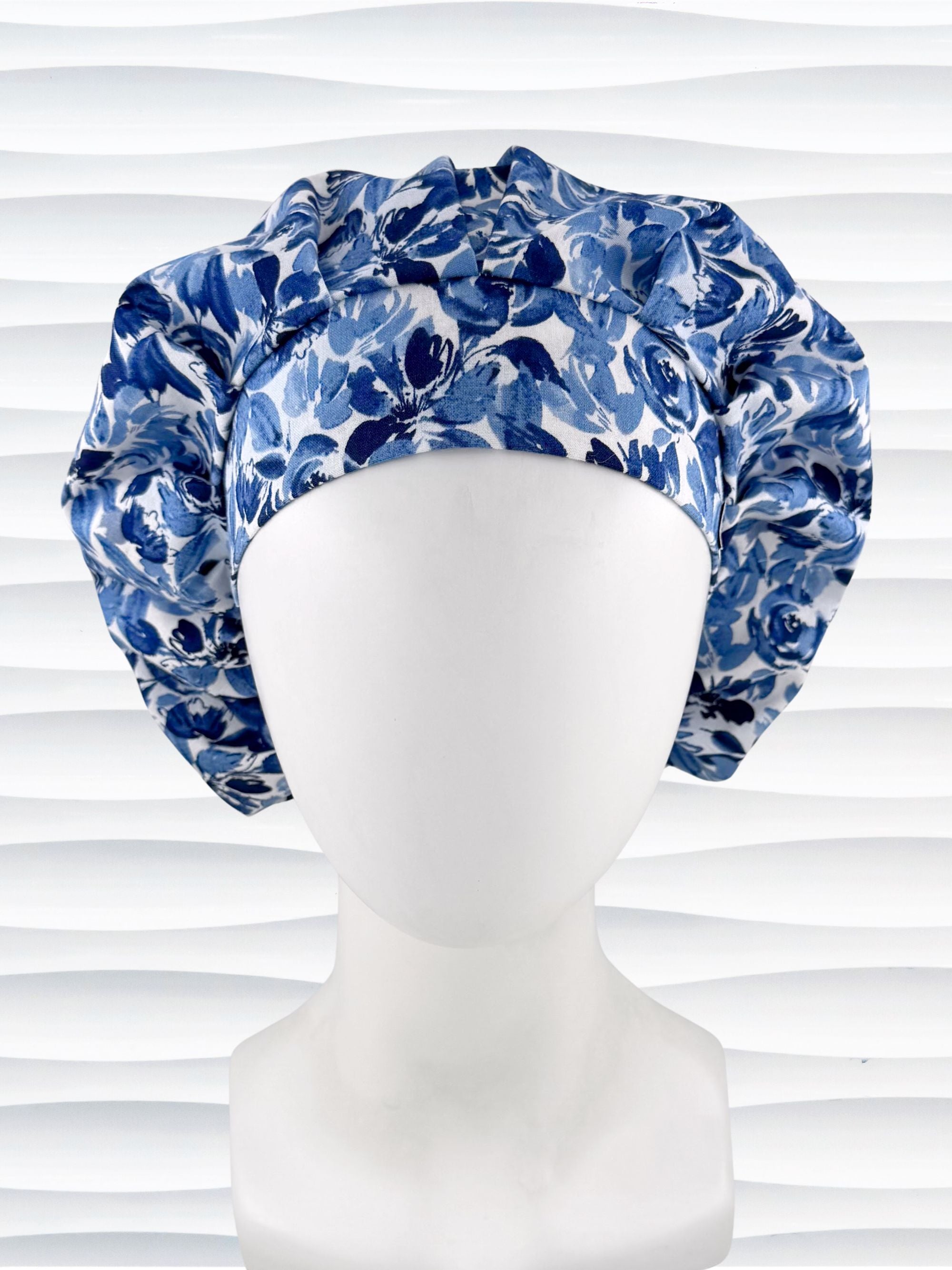 Bouffant style surgical scrub cap by JensCaps with flowers in varying shades of blue with a white background displayed on a white mannequin head.