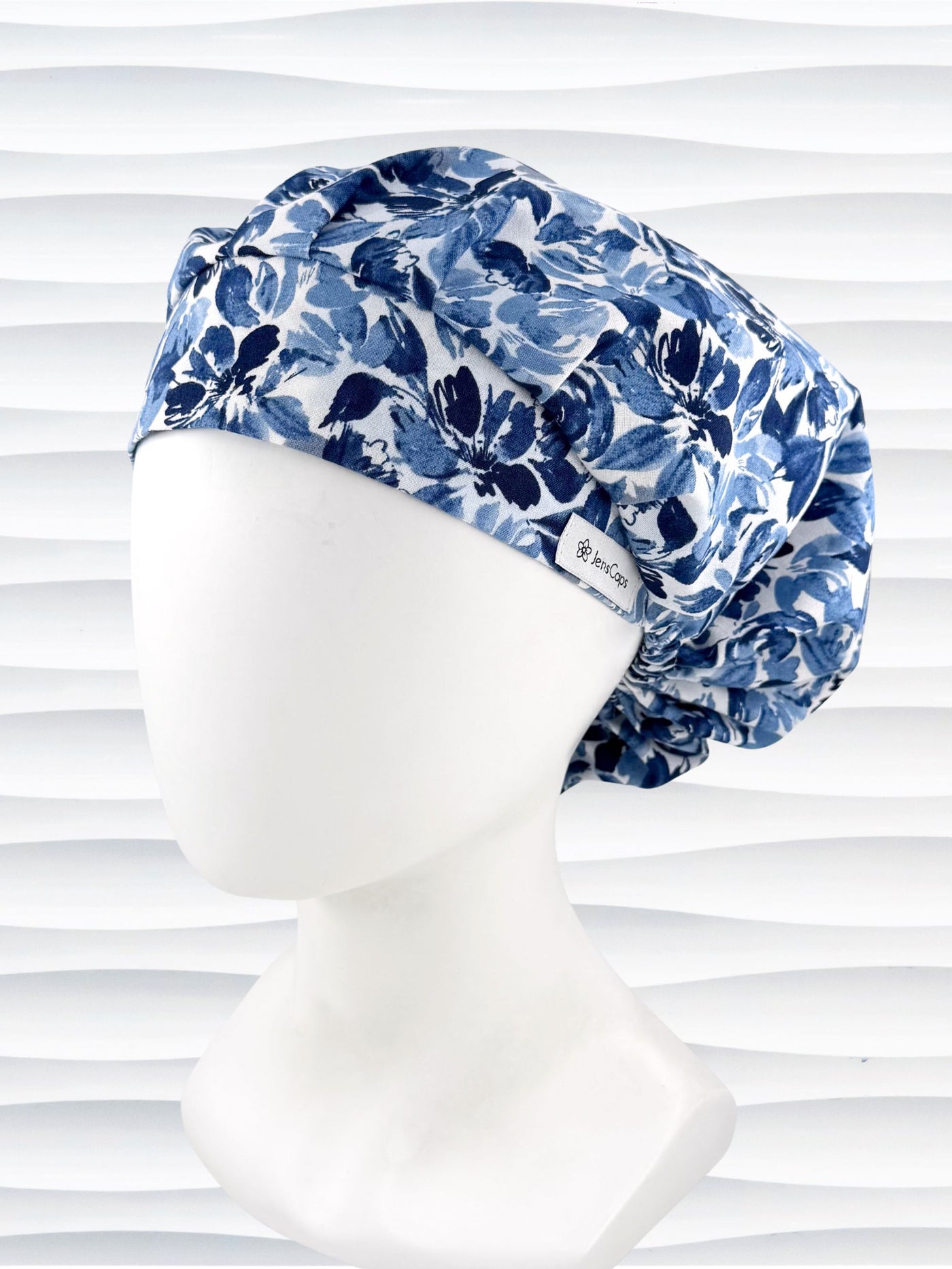 Bouffant style surgical scrub cap by JensCaps with flowers in varying shades of blue with a white background displayed on a white mannequin head.