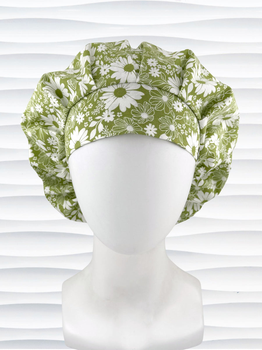 Bouffant style surgical scrub cap by JensCaps with white daisies and flowers all over a light green background cotton fabric and displayed on a mannequin head.