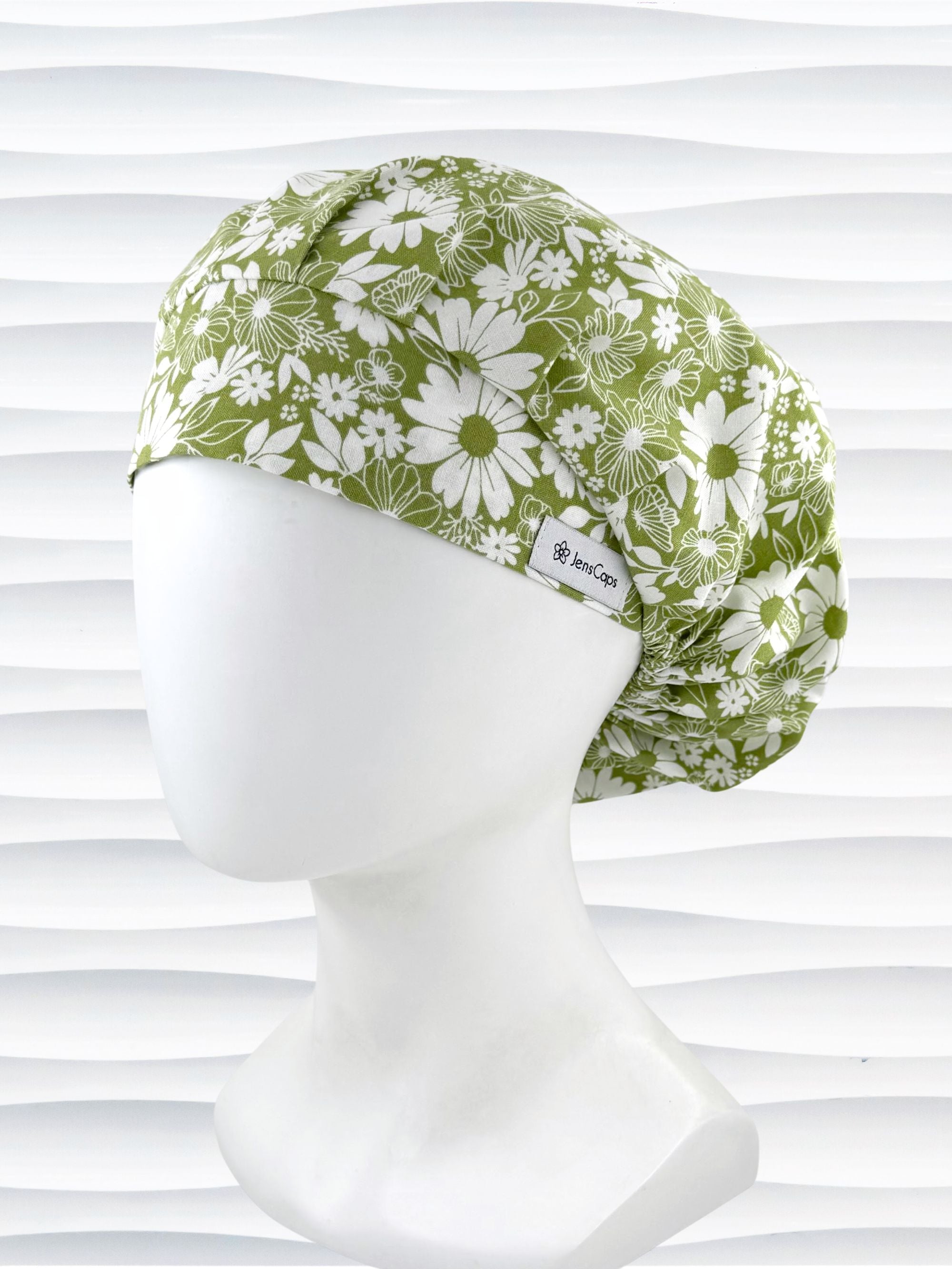 Bouffant style surgical scrub cap by JensCaps with white daisies and flowers all over a light green background cotton fabric and displayed on a mannequin head.