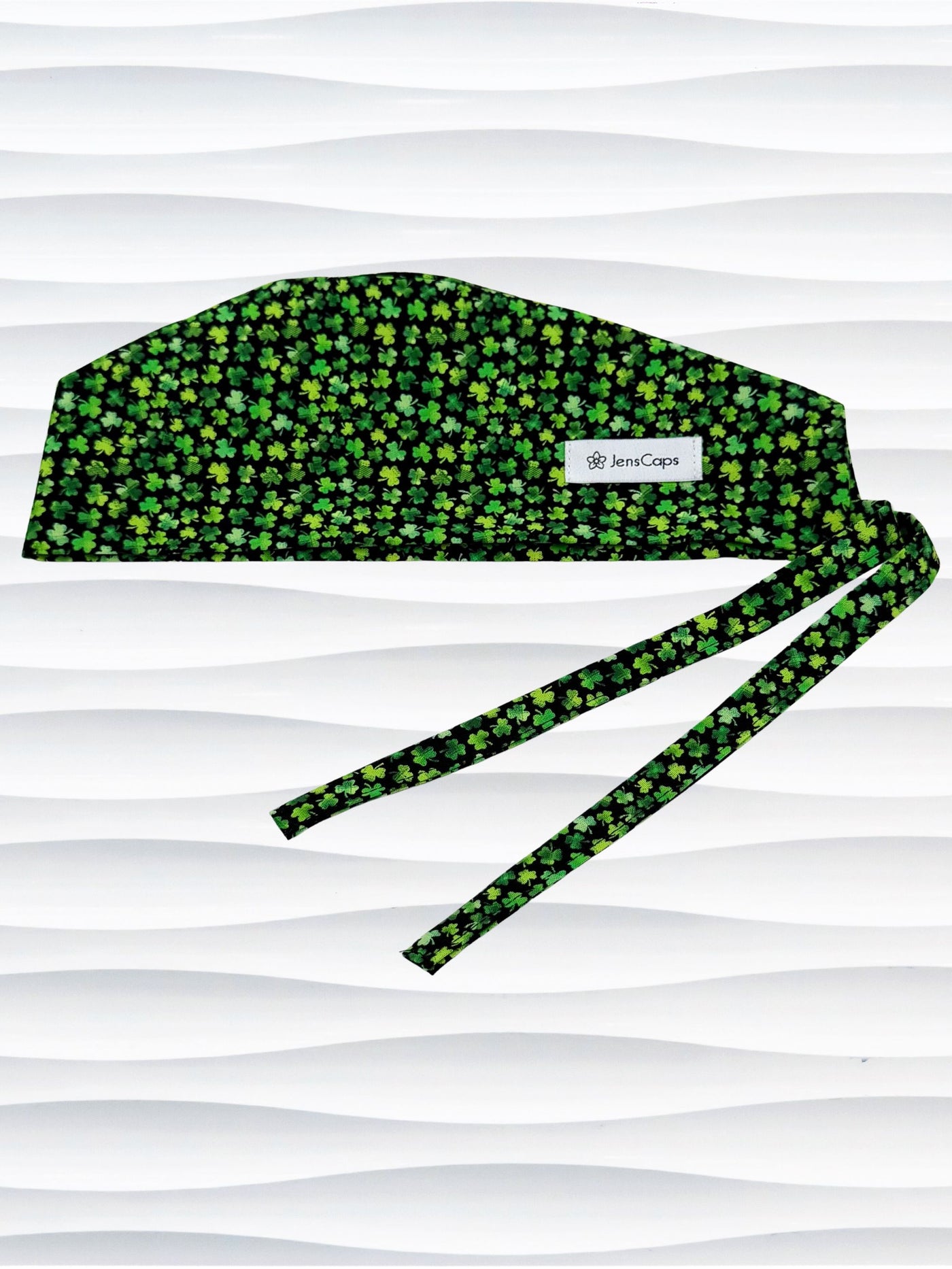 Mens style surgial scrub cap with small greencshamrocks on black cotton fabric and displayed on mannequin head.