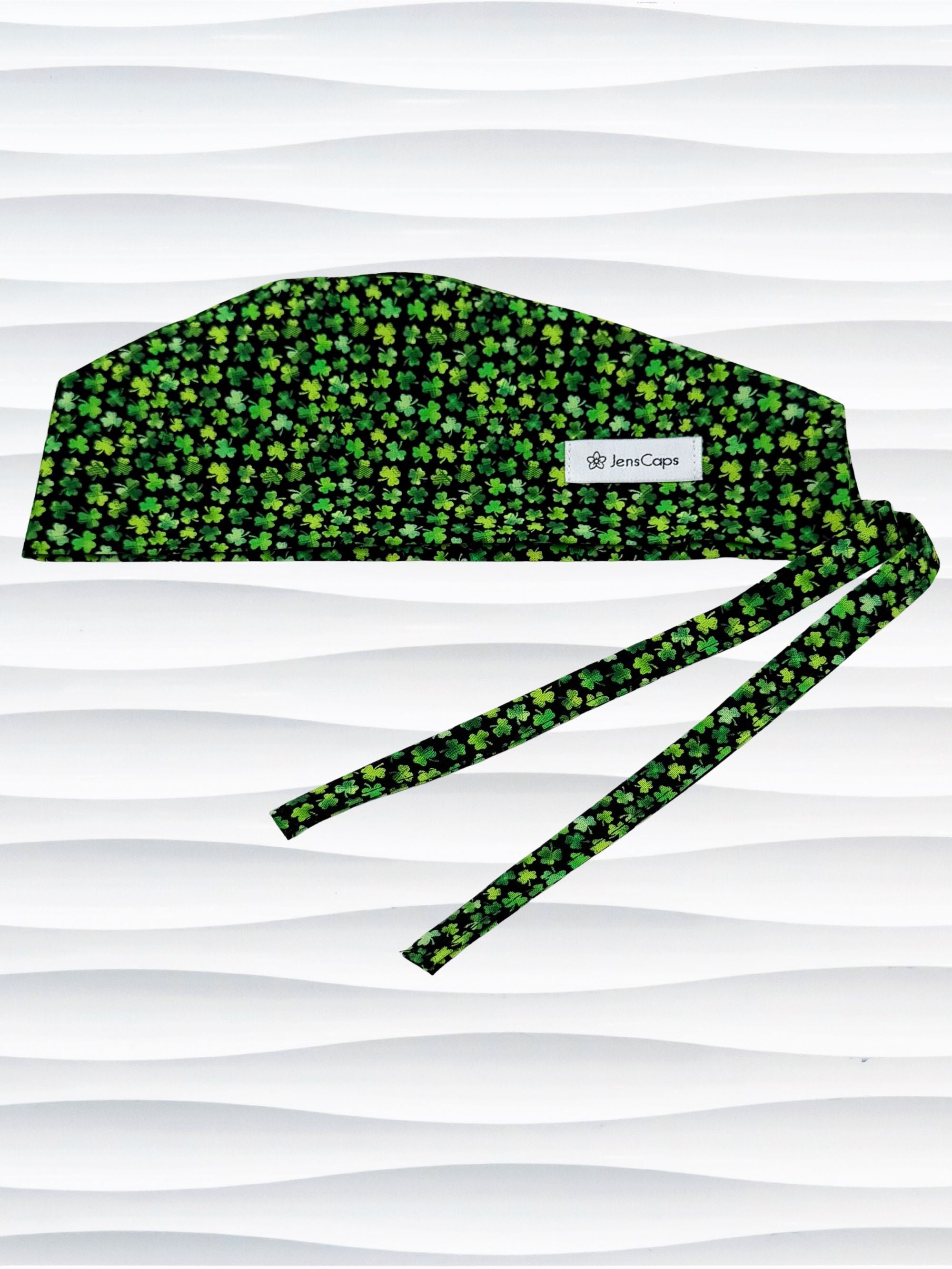 Mens style surgial scrub cap with small greencshamrocks on black cotton fabric and displayed on mannequin head.