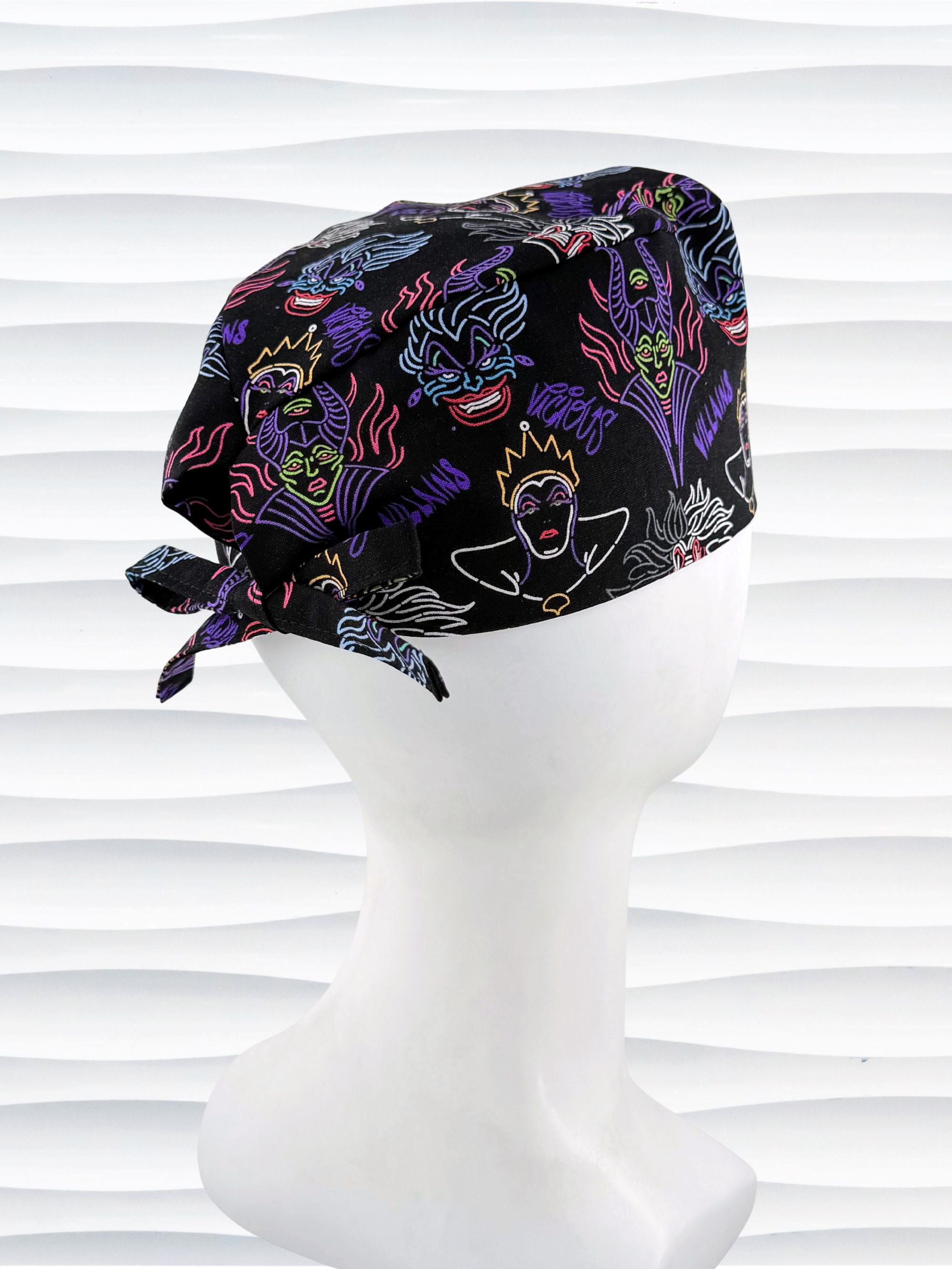 Mens style surgical scrub skull cap with neon colors of iconic villains and queens all over black cotton fabric and displayed on mannequin head.