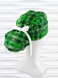 Green plaid ponytail style surgical scrub cap with shamrock pattern on a mannequin head against a white background