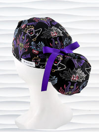 Ponytail style surgical scrub cap with neon colors of iconic villains all over black cotton fabric, finished with a ribbon tie and displayed on mannequin head.