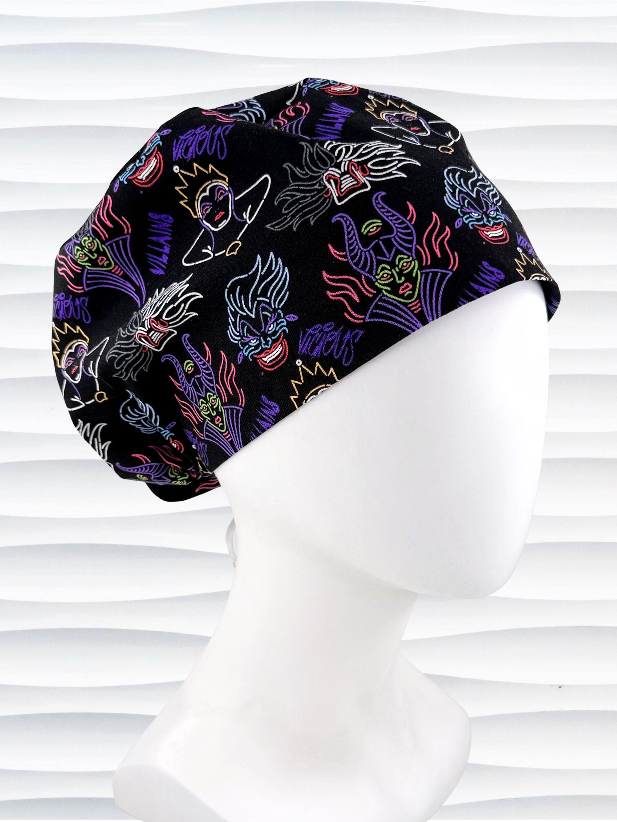 Euro Pixie style surgical scrub cap by JensCaps with neon colors of iconic villains all over black cotton fabric and displayed on mannequin head.