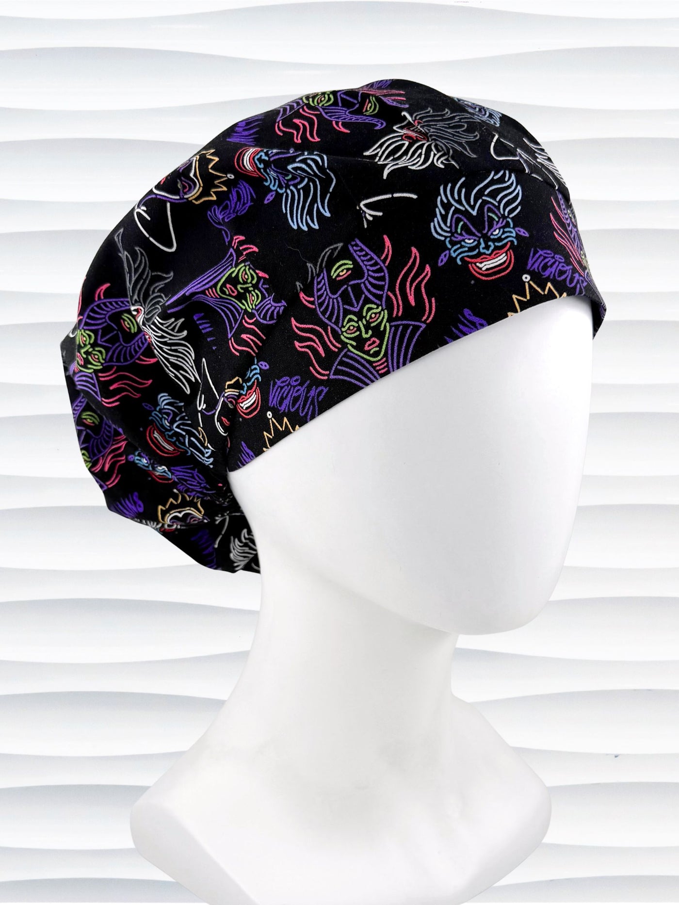 Bouffant style surgical scrub cap with neon colors of iconic villains all over black cotton fabric and displayed on mannequin head.