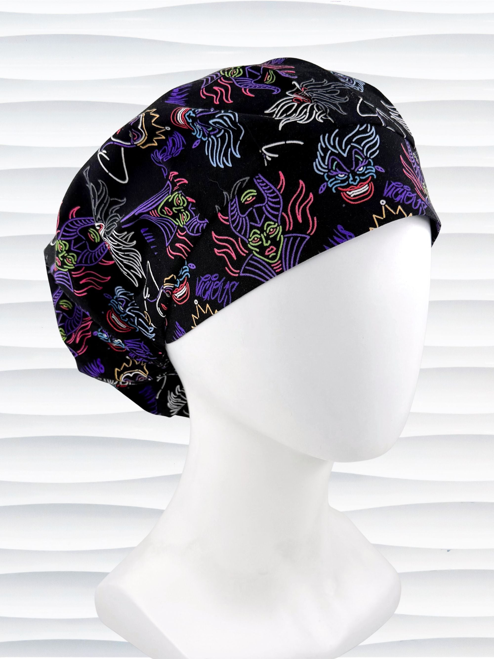 Bouffant style surgical scrub cap with neon colors of iconic villains all over black cotton fabric and displayed on mannequin head.
