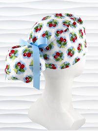 Ponytail surgical scrub cap by JensCaps with red cherries blue polka dots on white cotton fabric, finished with a ribbon tie, and diplayed on a mannequin head.