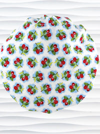 Bouffant style surgical scrub cap by JensCaps with red cherries and blue polka dots on white cotton fabric and displayed on a mannequin head.