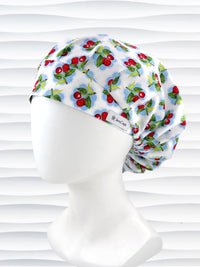 Bouffant style surgical scrub cap by JensCaps with red cherries and blue polka dots on white cotton fabric and displayed on a mannequin head.