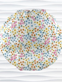 A white fabric bouffant style surgical cap by JensCaps with a colorful floral print, displayed on a white mannequin head against a white wavy background.