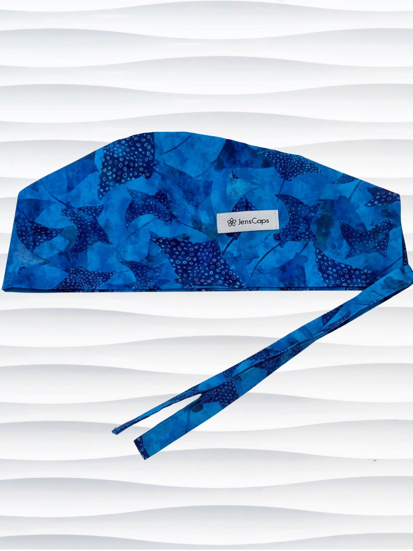Tie back surgeon style scrub cap by JensCaps with blue fish and ocean stingrays on cotton fabric and displayed on a white mannequin head.