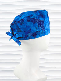 Tie back surgeon style scrub cap by JensCaps with blue fish and ocean stingrays on cotton fabric and displayed on a white mannequin head.