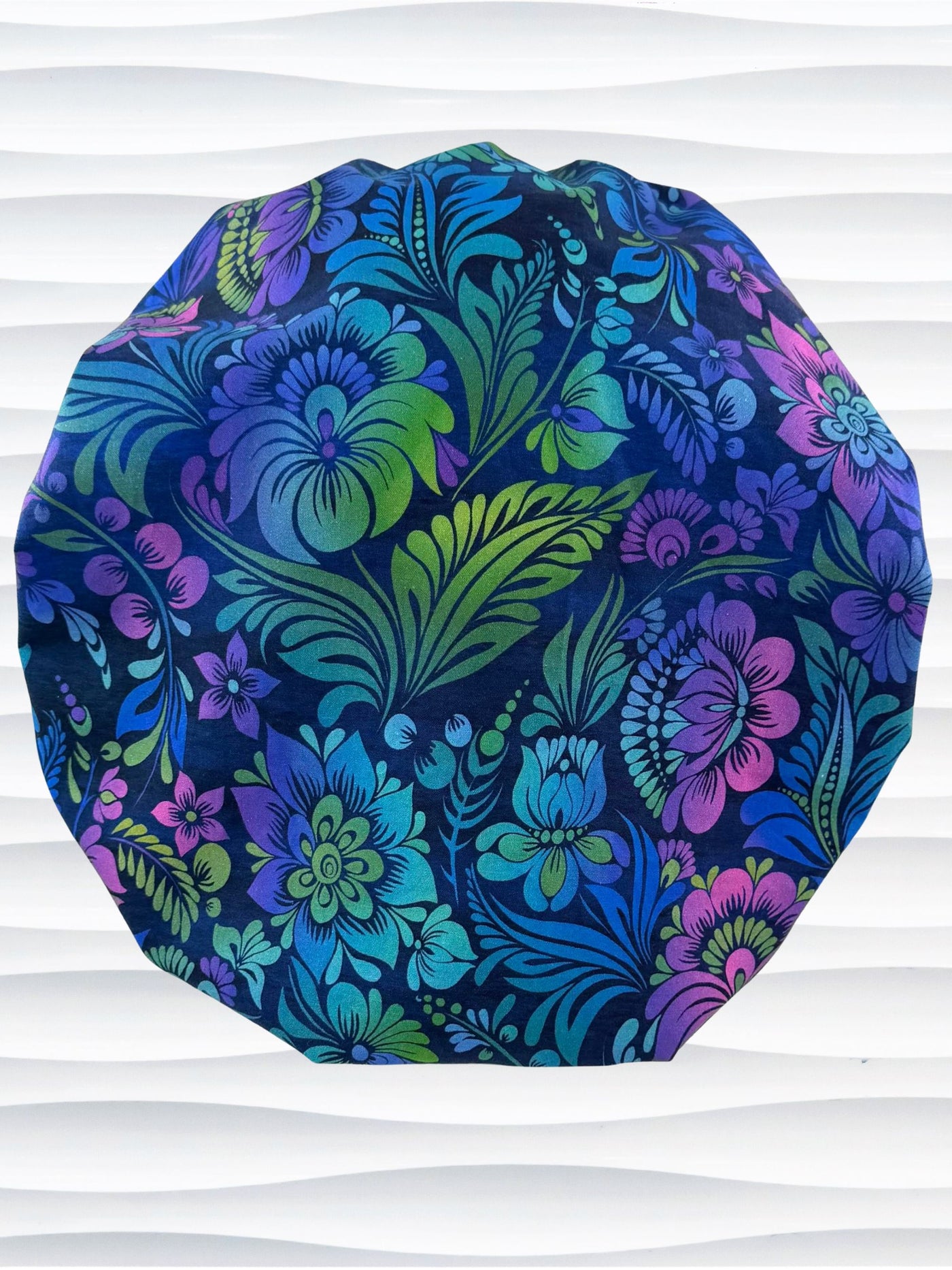 Bouffant style surgical scrub cap by JensCaps with an allover floral pattern in dark blue, purple, emerald, and turquoise and displayed on a mannequin head.