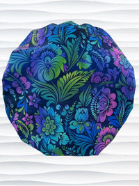 Bouffant style surgical scrub cap by JensCaps with an allover floral pattern in dark blue, purple, emerald, and turquoise and displayed on a mannequin head.