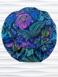 Euro Pixie style surgical scrub cap by JensCaps with an allover floral pattern in dark blue, purple, emerald, and turquoise and displayed on a mannequin head.