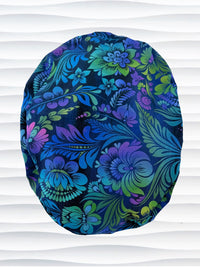 Euro Pony style surgical scrub cap by JensCaps with an allover floral pattern in dark blue, purple, emerald, and turquoise and displayed on a mannequin head.