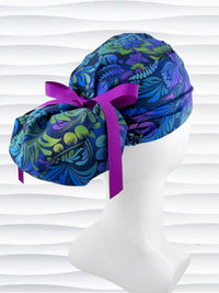 Euro Pony style surgical scrub cap by JensCaps with an allover floral pattern in dark blue, purple, emerald, and turquoise and displayed on a mannequin head.
