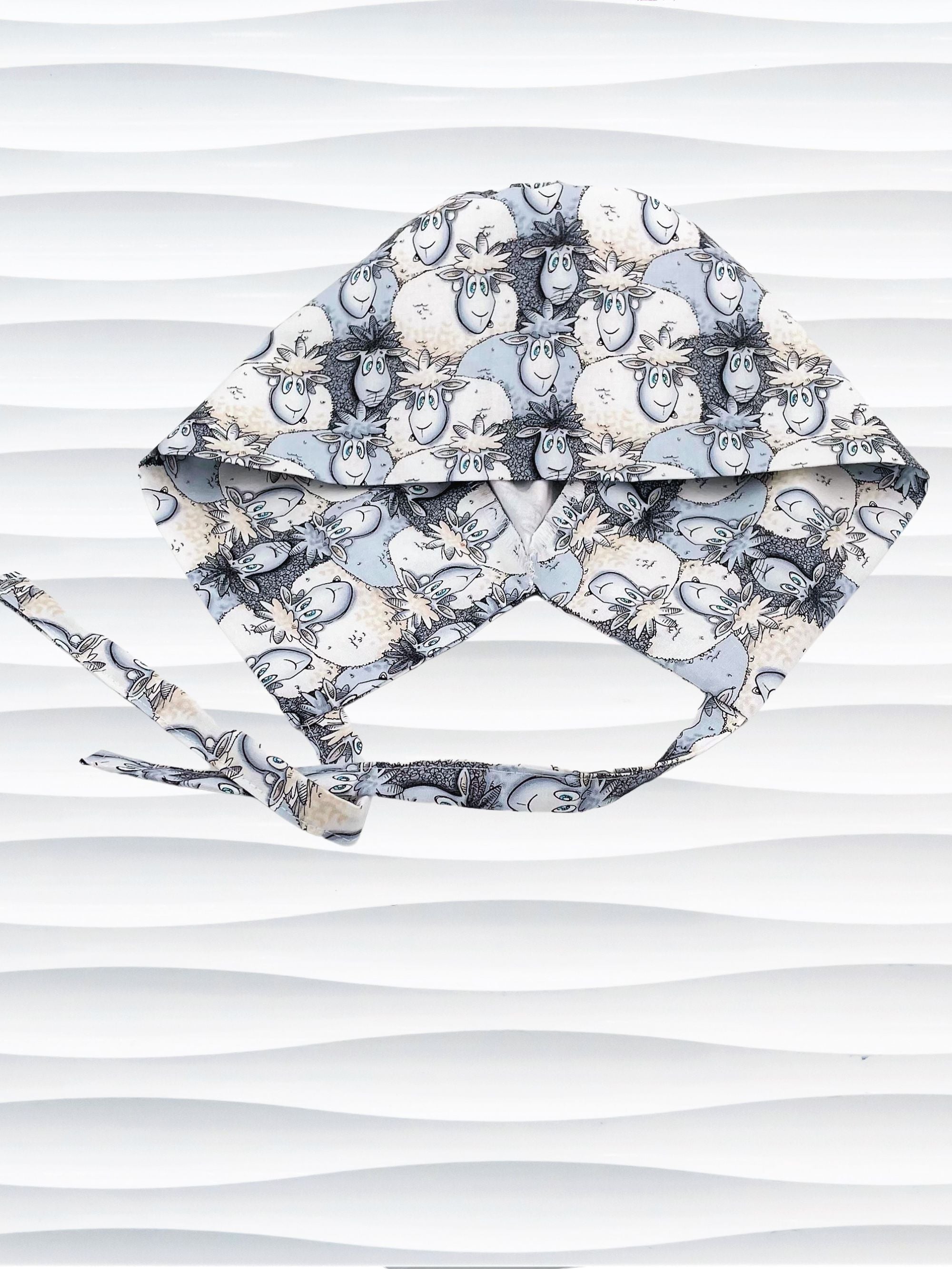 Surgeon style surgical scrub cap hat with a cute herd of cartoon sheep in blues and white on cotton fabric.