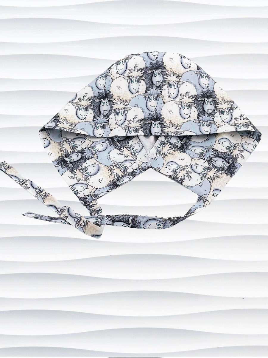 Surgeon style surgical scrub cap hat with a cute herd of cartoon sheep in blues and white on cotton fabric.