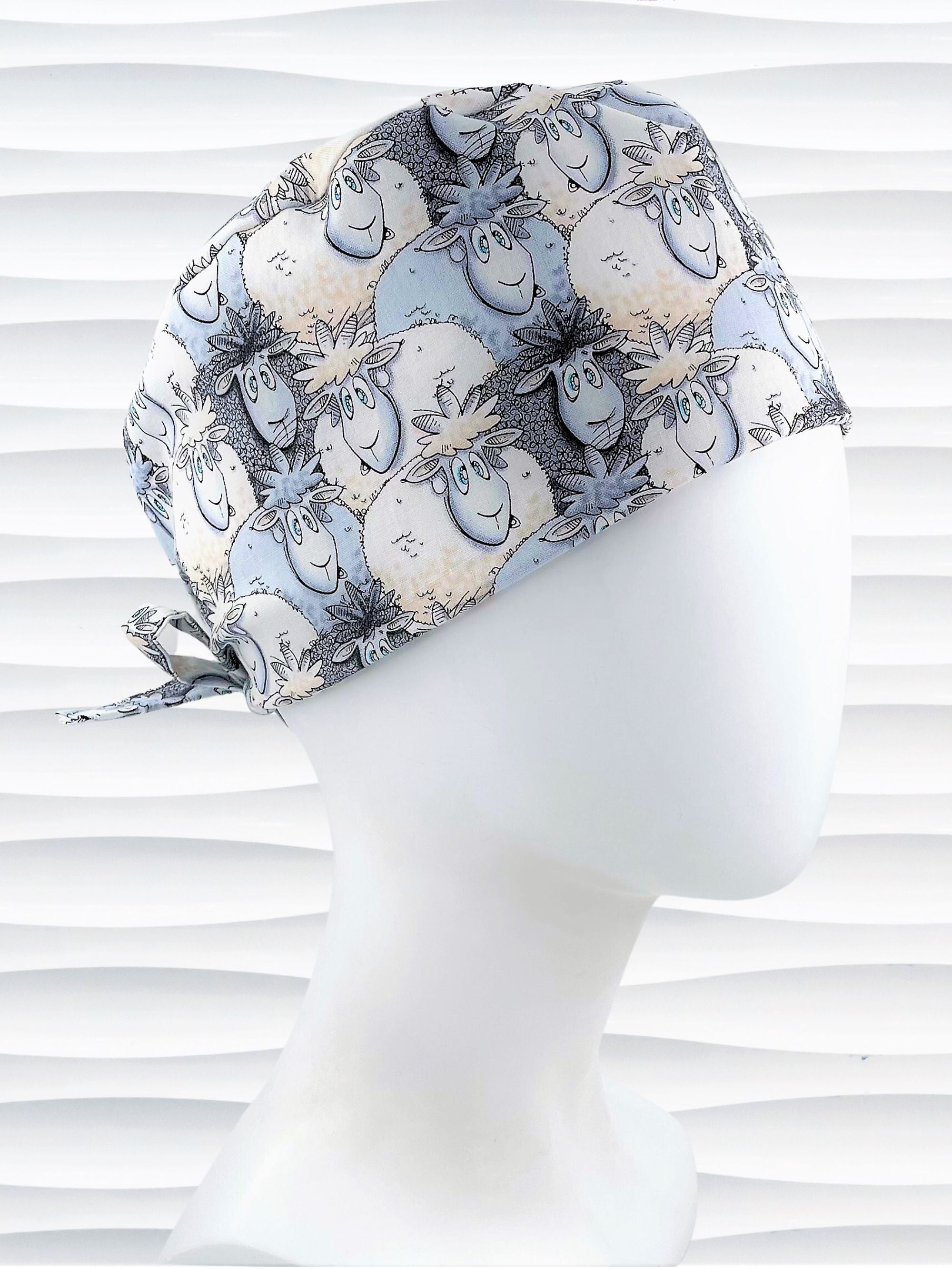 Surgeon style surgical scrub cap hat with a cute herd of cartoon sheep in blues and white on cotton fabric.