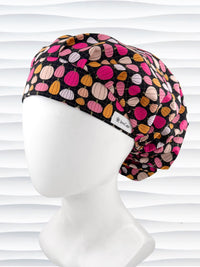 Bouffant style surgical scrub cap by JensCaps with pink and orange pumpkins on black cotton fabric and displayed on a mannequin head.
