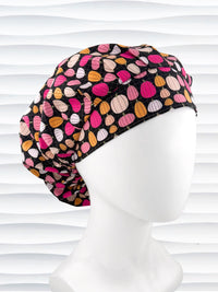 Bouffant style surgical scrub cap by JensCaps with pink and orange pumpkins on black cotton fabric and displayed on a mannequin head.