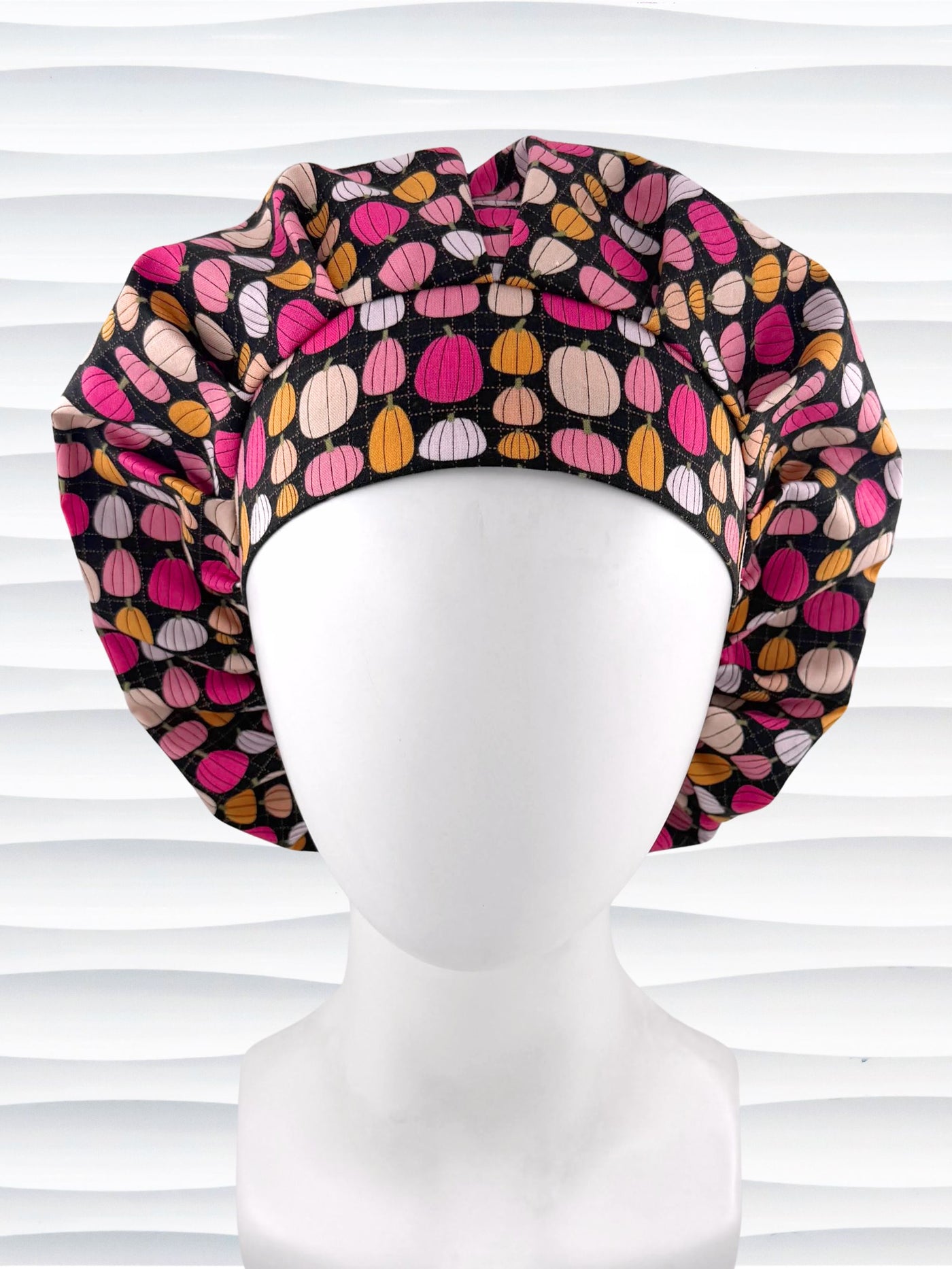 Bouffant style surgical scrub cap by JensCaps with pink and orange pumpkins on black cotton fabric and displayed on a mannequin head.