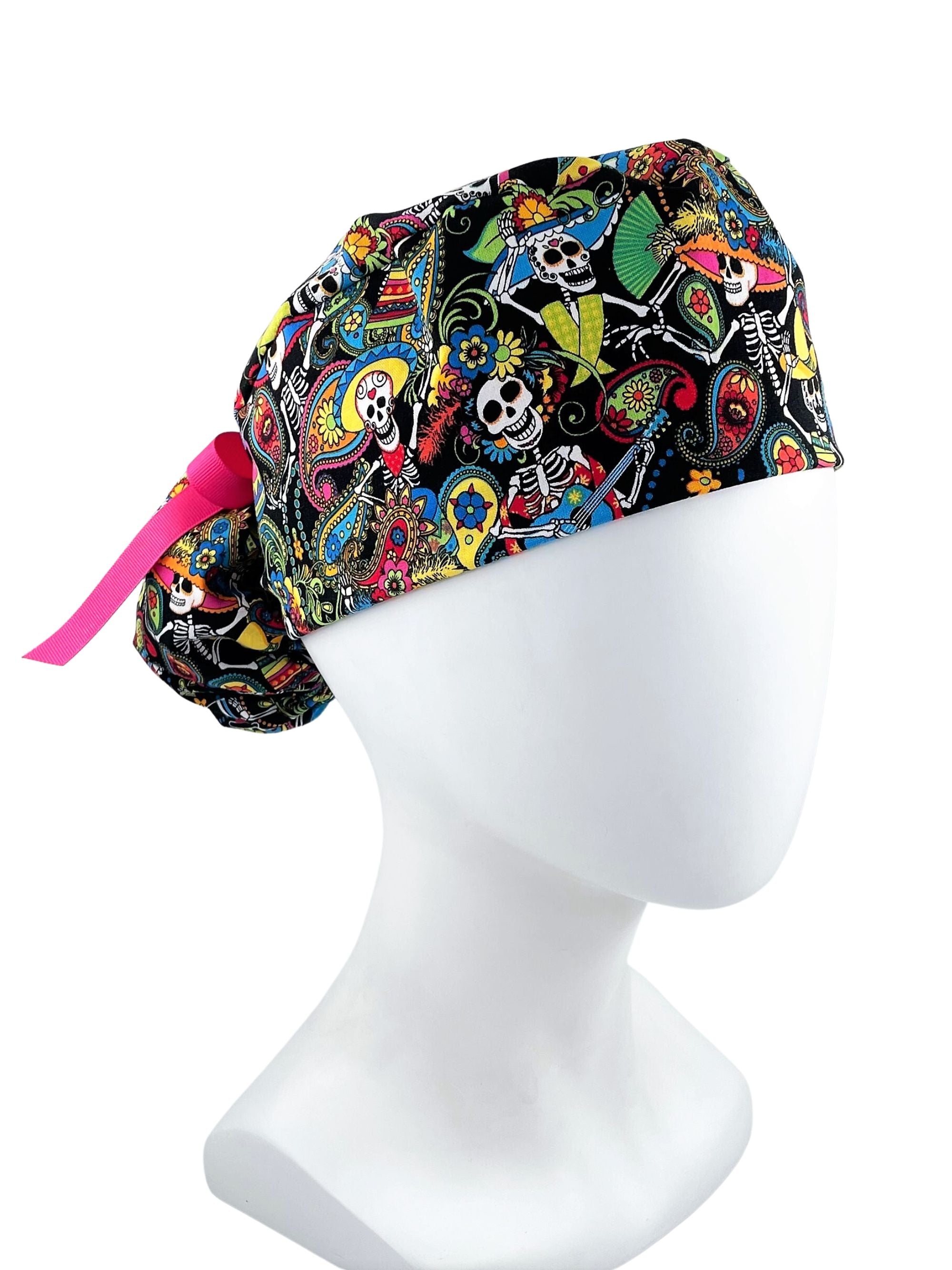 Ponytail scrub cap hat with day of the dead in bright colors on black cotton fabric and finished with grosgrain ribbon ties.