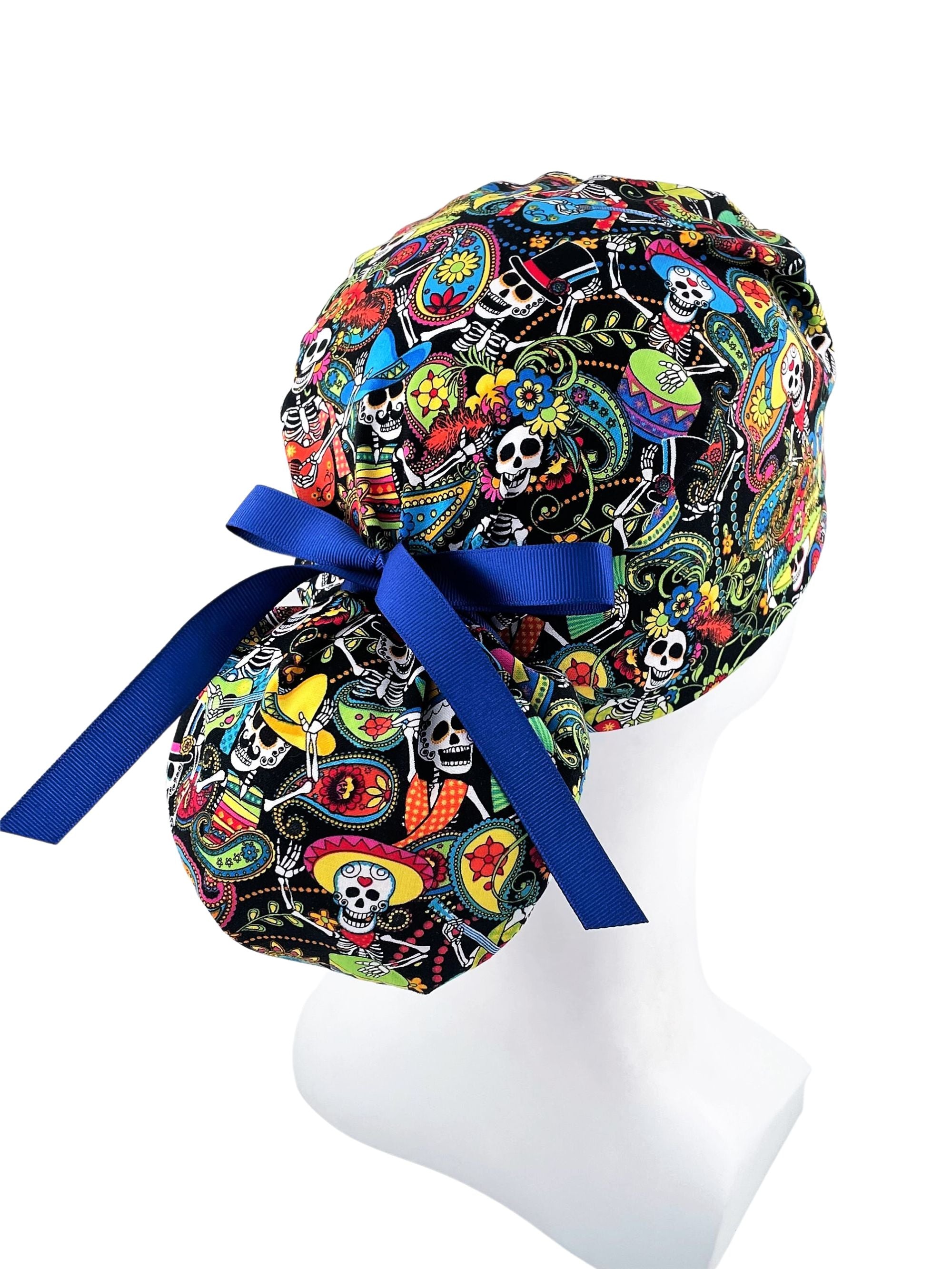 Ponytail scrub cap hat with day of the dead in bright colors on black cotton fabric and finished with grosgrain ribbon ties.