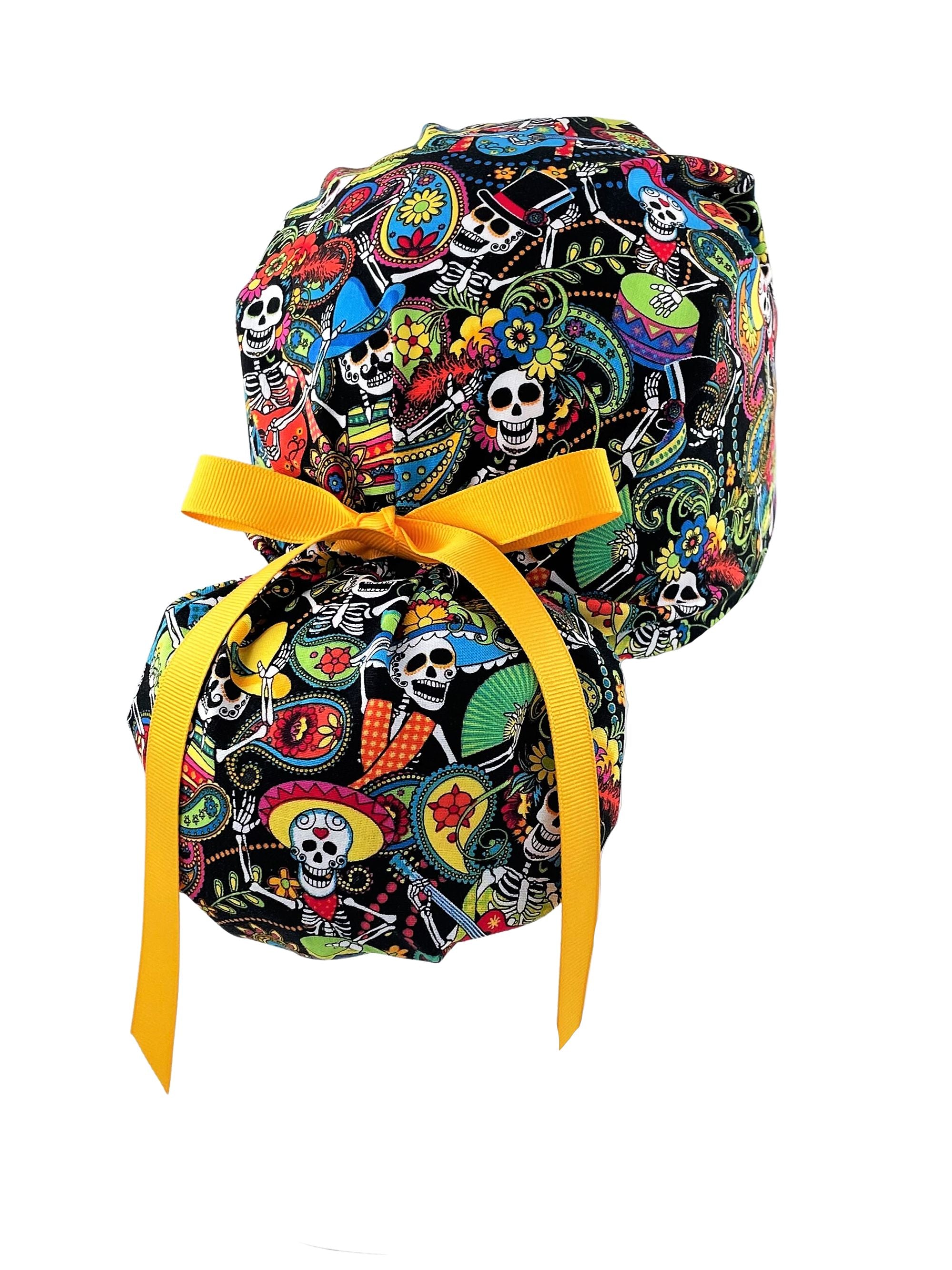 Ponytail scrub cap hat with day of the dead in bright colors on black cotton fabric and finished with grosgrain ribbon ties.