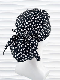 Ponytail style scrub cap hat with white butterflies on black cotton fabric.