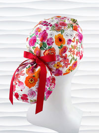 Ponytail style scrub cap with bright flowers on white cotton fabric and grosgrain ribbon ties