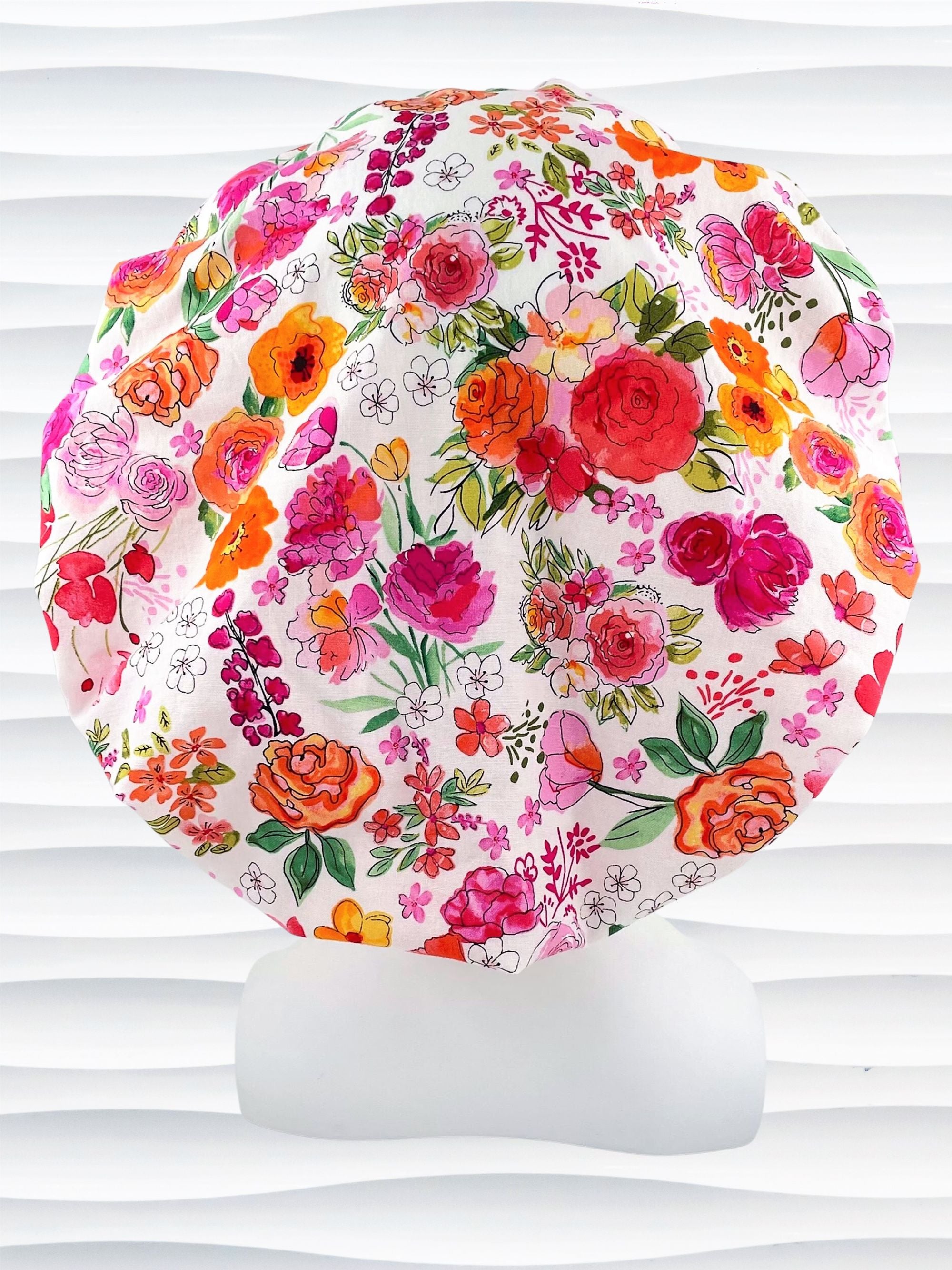 Bouffant style surgical scrub cap hat with pink, red, yellow, white, and orange flowers on white cotton fabric.