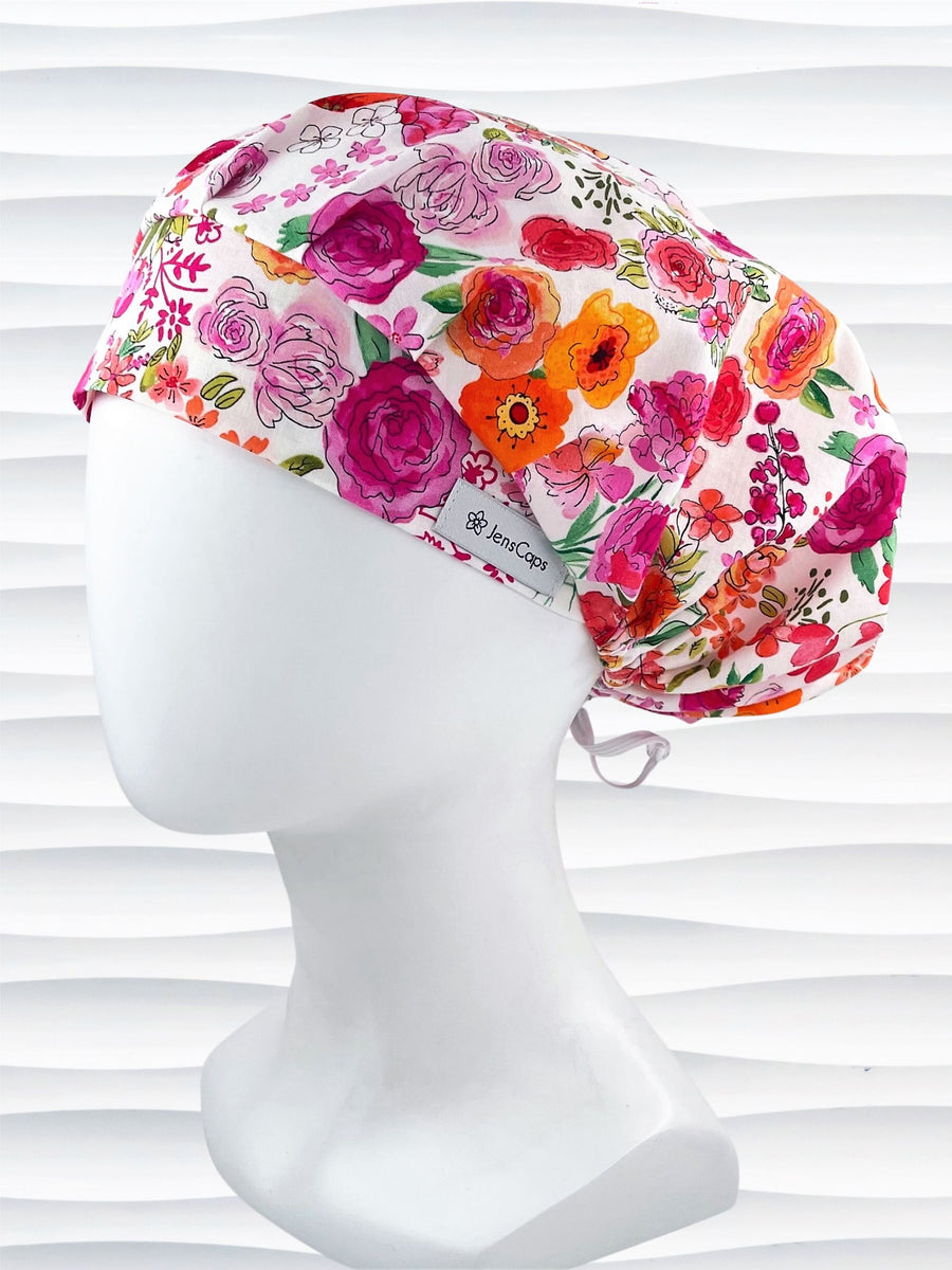 Bouffant style surgical scrub cap hat with pink, red, yellow, white, and orange flowers on white cotton fabric.