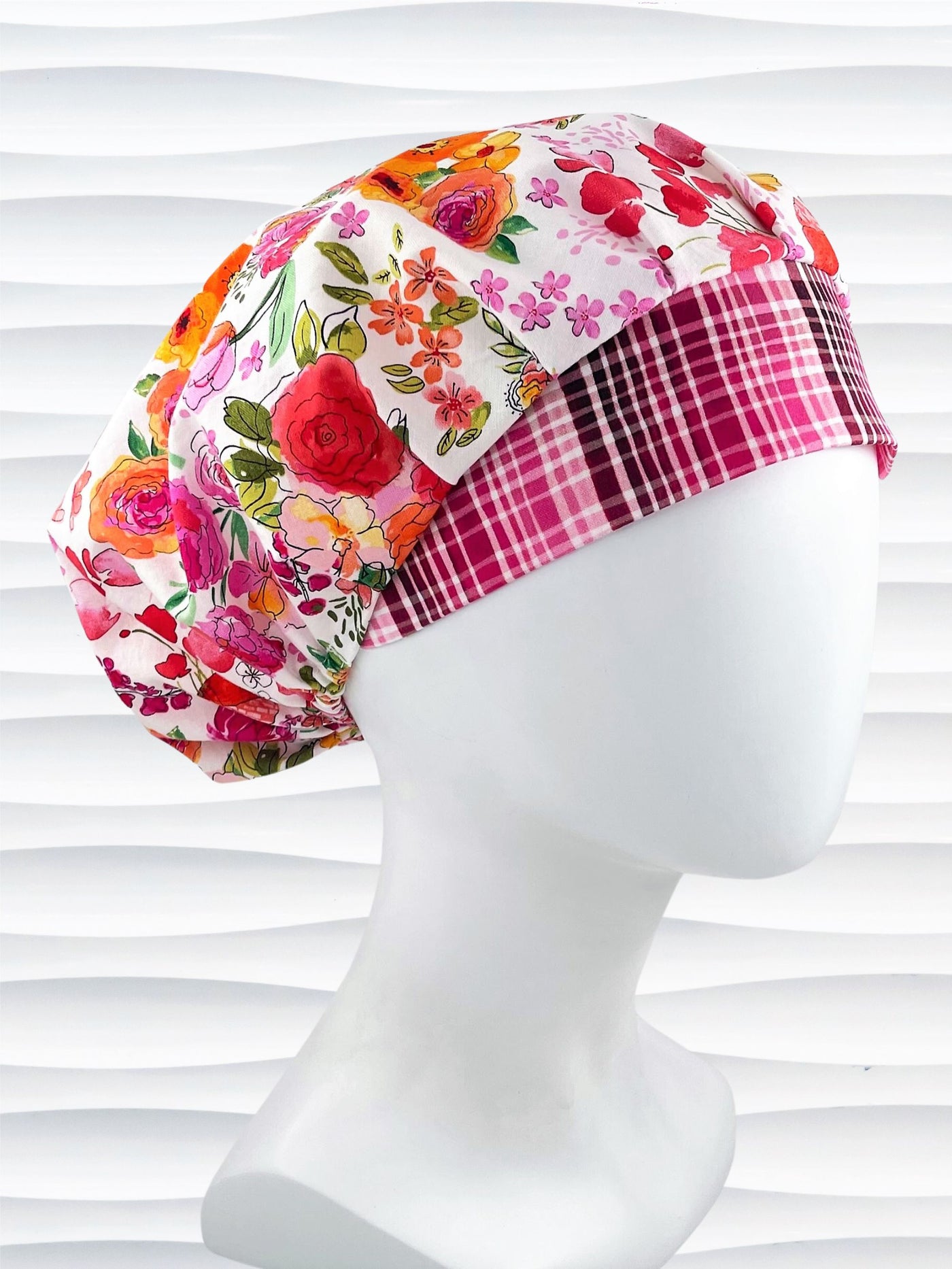 Bouffant style surgical scrub cap hat with pink, red, yellow, white, and orange flowers on white cotton fabric.