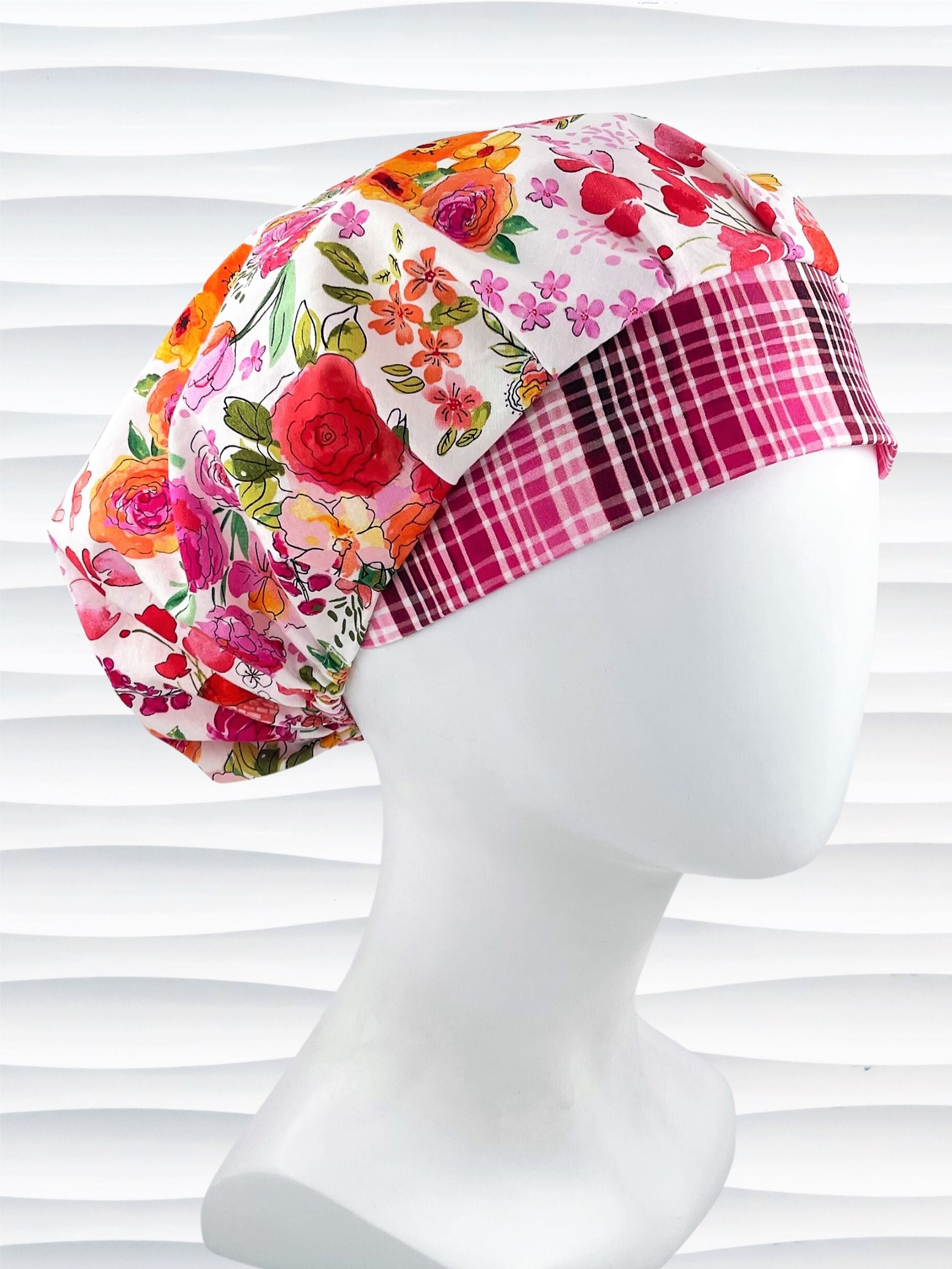 Bouffant style surgical scrub cap hat with pink, red, yellow, white, and orange flowers on white cotton fabric.