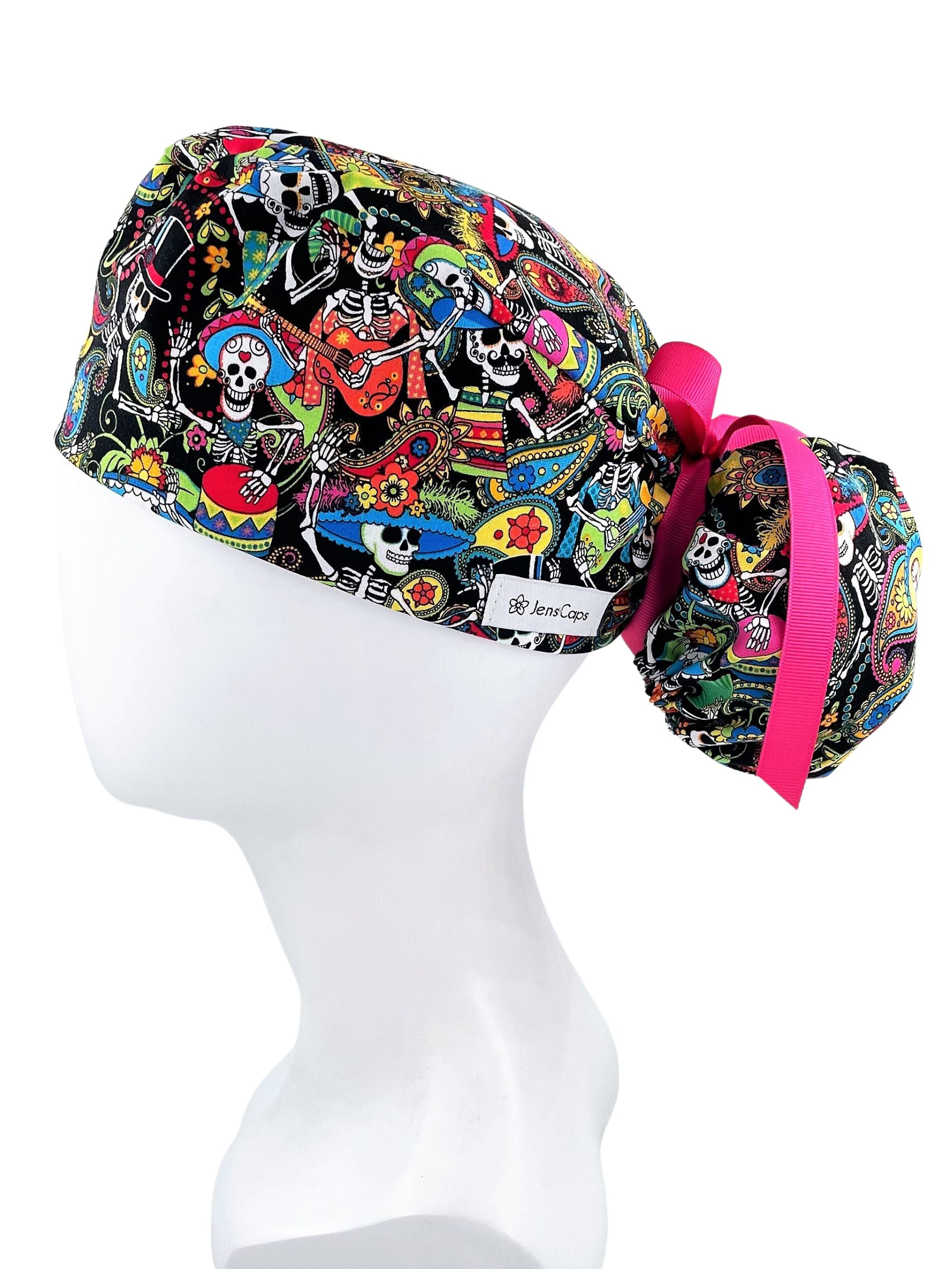 Ponytail scrub cap hat with day of the dead in bright colors on black cotton fabric and finished with grosgrain ribbon ties.