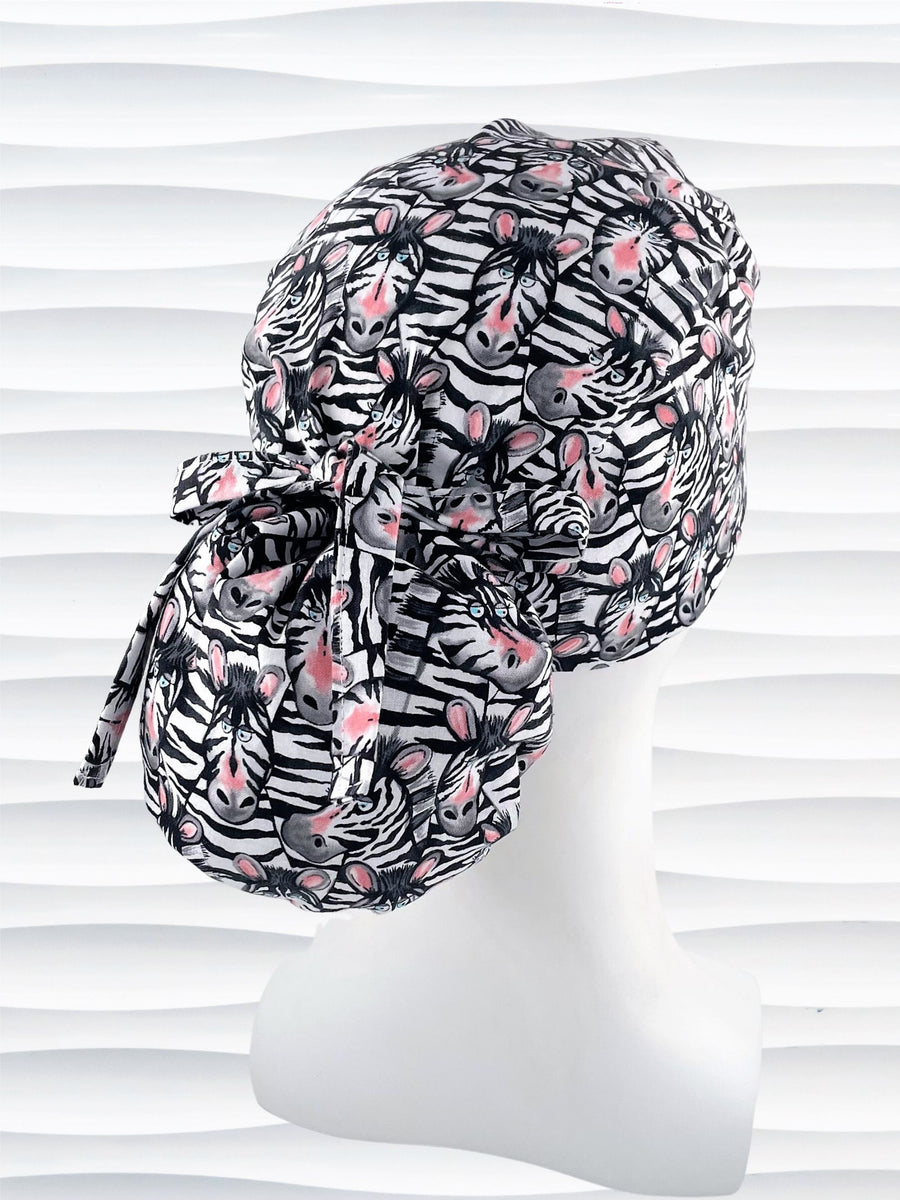 Ponytail style surgical scrub cap with black and white zebras with pink faces on premium cotton fabric.