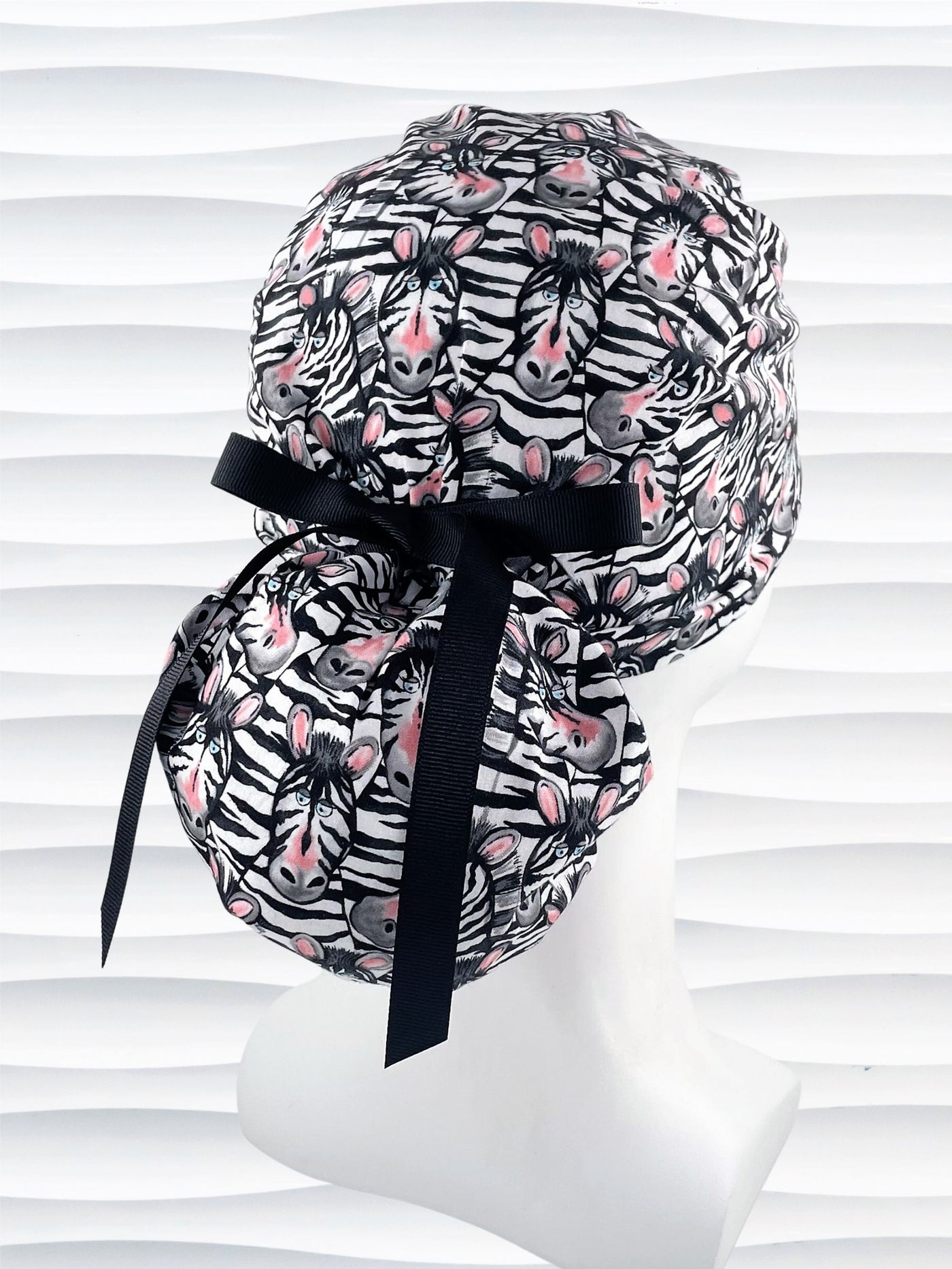 Ponytail style surgical scrub cap with black and white zebras with pink faces on premium cotton fabric.