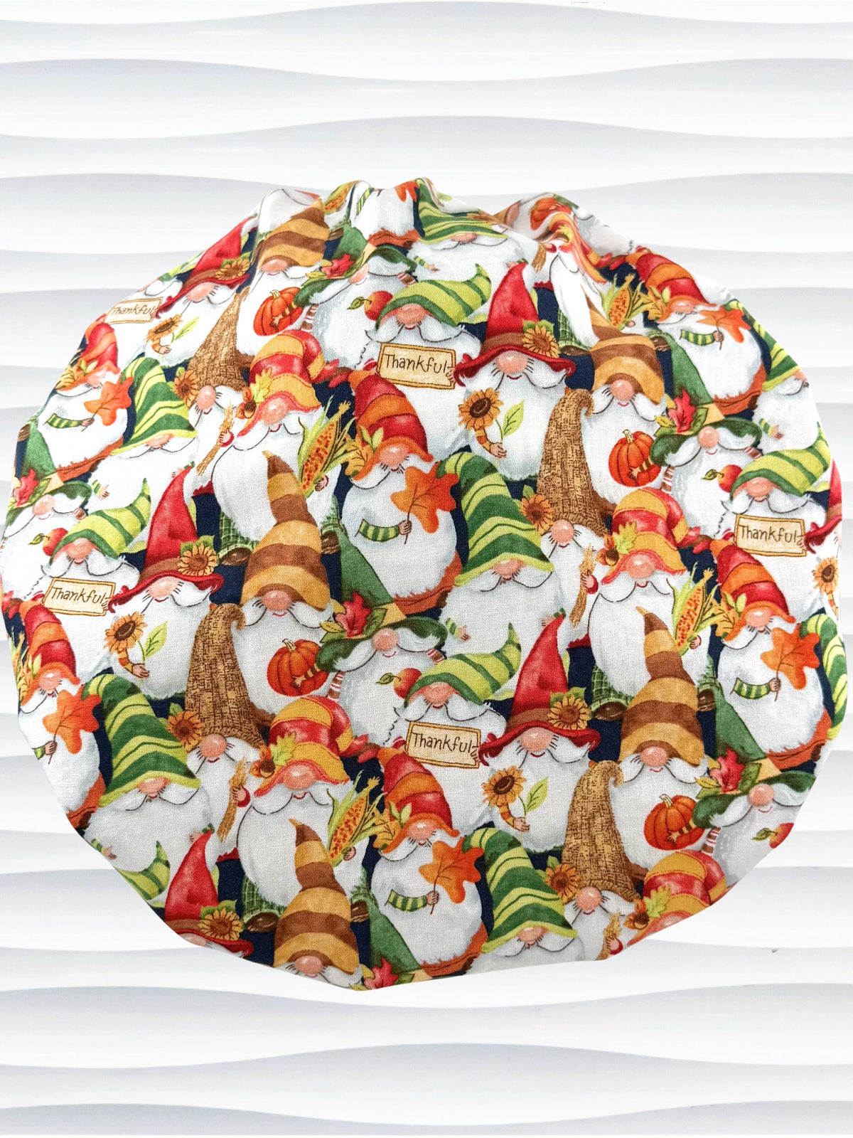 Bouffant style surgical scrub cap with gnomes in fall colors holding sunflowers and signs that say thankful and displayed on a mannequin head.