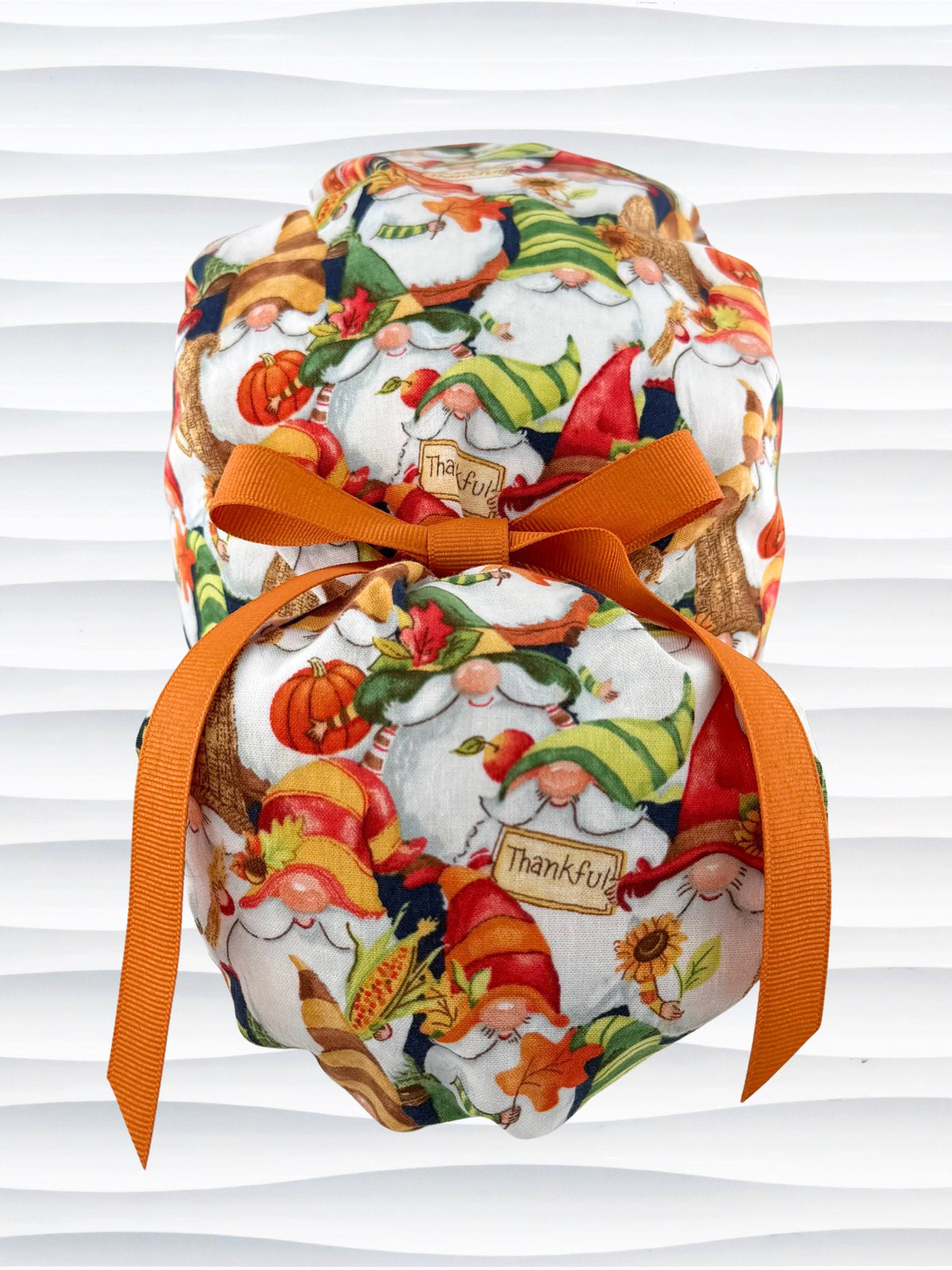 Euro Pony style surgical scrub cap with gnomes in fall colors holding sunflowers and signs that say thankful, tied with a ribbon, and displayed on a mannequin head.