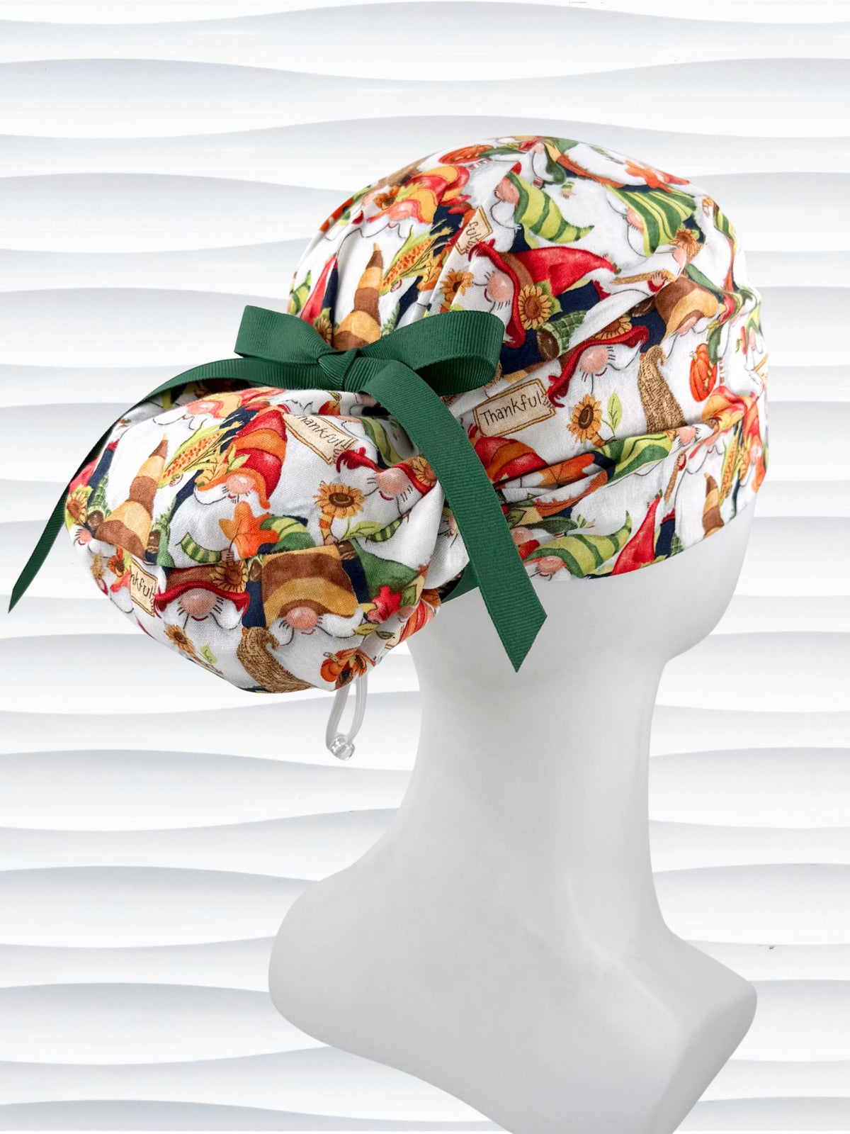 Euro Pony style surgical scrub cap with gnomes in fall colors holding sunflowers and signs that say thankful, tied with a ribbon, and displayed on a mannequin head.