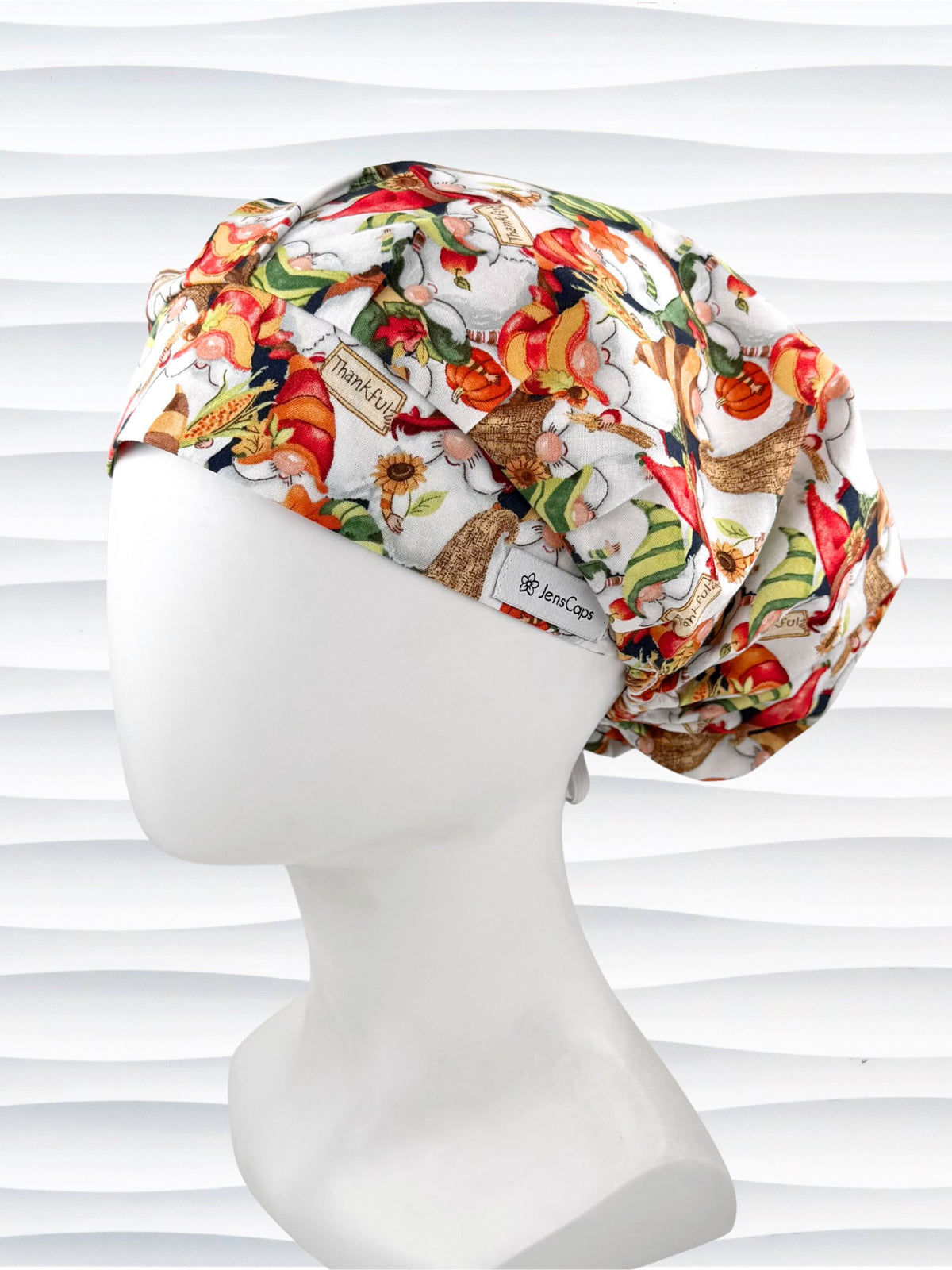 Bouffant style surgical scrub cap with gnomes in fall colors holding sunflowers and signs that say thankful and displayed on a mannequin head.