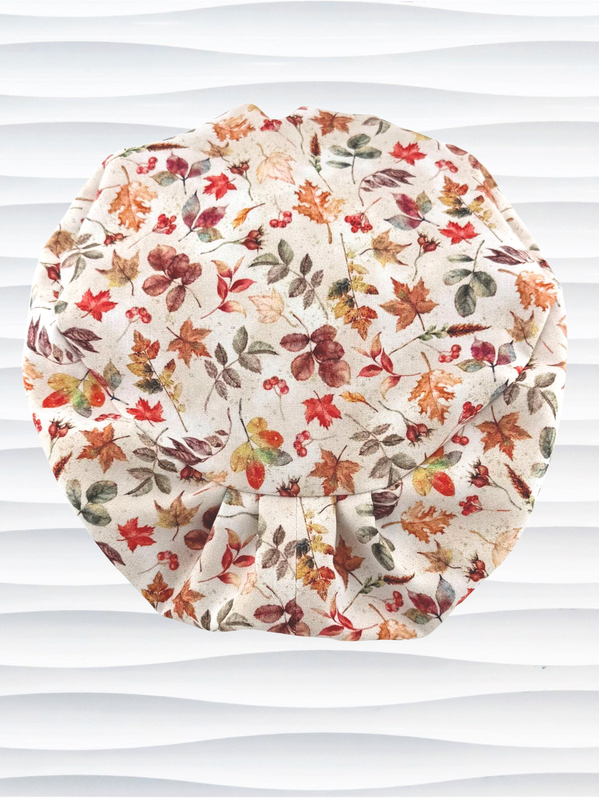 Euro Pixie style surgical scrub cap with an assortment of autumn eaves in fall colors all over a light background and displayed on a white mannequin head.
