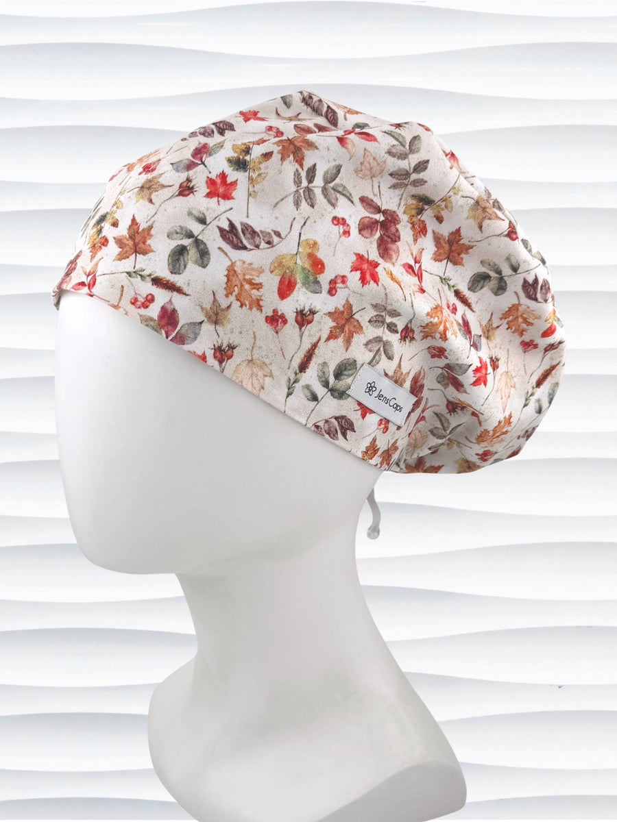 Euro Pixie style surgical scrub cap with an assortment of autumn eaves in fall colors all over a light background and displayed on a white mannequin head.